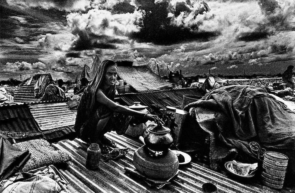 Woman cooking on rooftop in the aftermath of a cyclone, Jinjira, Dhaka, 1988. (Bangladesh, 1988. Truth to Power, Rubin Museum of Art, New York. Image courtesy of the artist.)