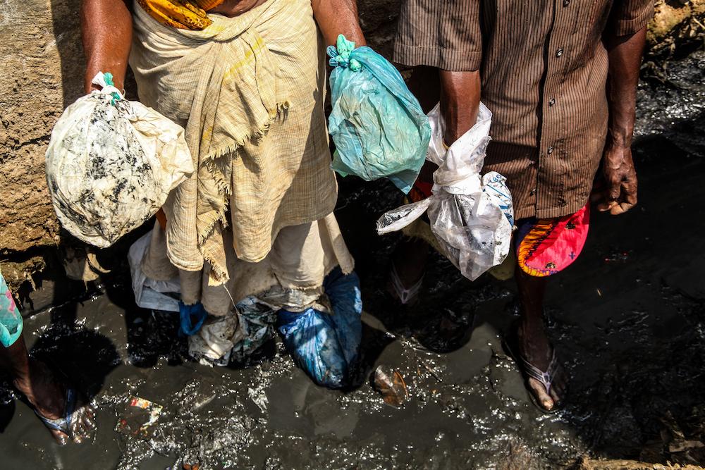 Although manual scavenging is banned under the Employment of Manual Scavengers and Construction of Dry Latrines (Prohibition) Act, 1993, the practice still continues. Employees are not equipped with adequate protective gear, often being forced to use makeshift covers such as plastic bags as seen here. (Pudukkottai, Tamil Nadu, 10 March 2016.)